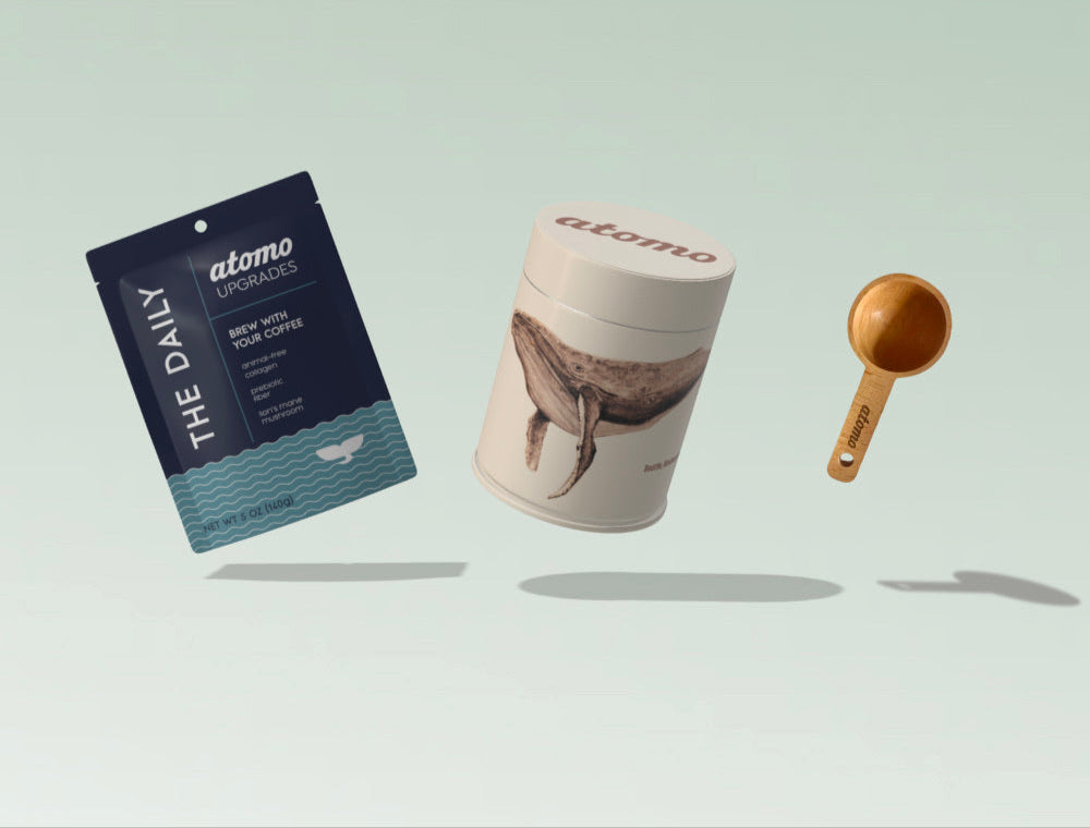 Atomo supplement packaging including a blue packet, white container, and gold scoop on a light gray background